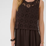 Woman wearing a brown crochet top over a dress on a white background