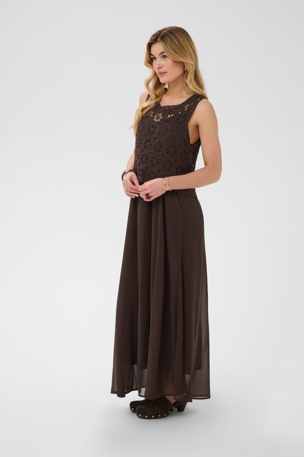 Woman wearing a brown dress with crochet detailing on a white background