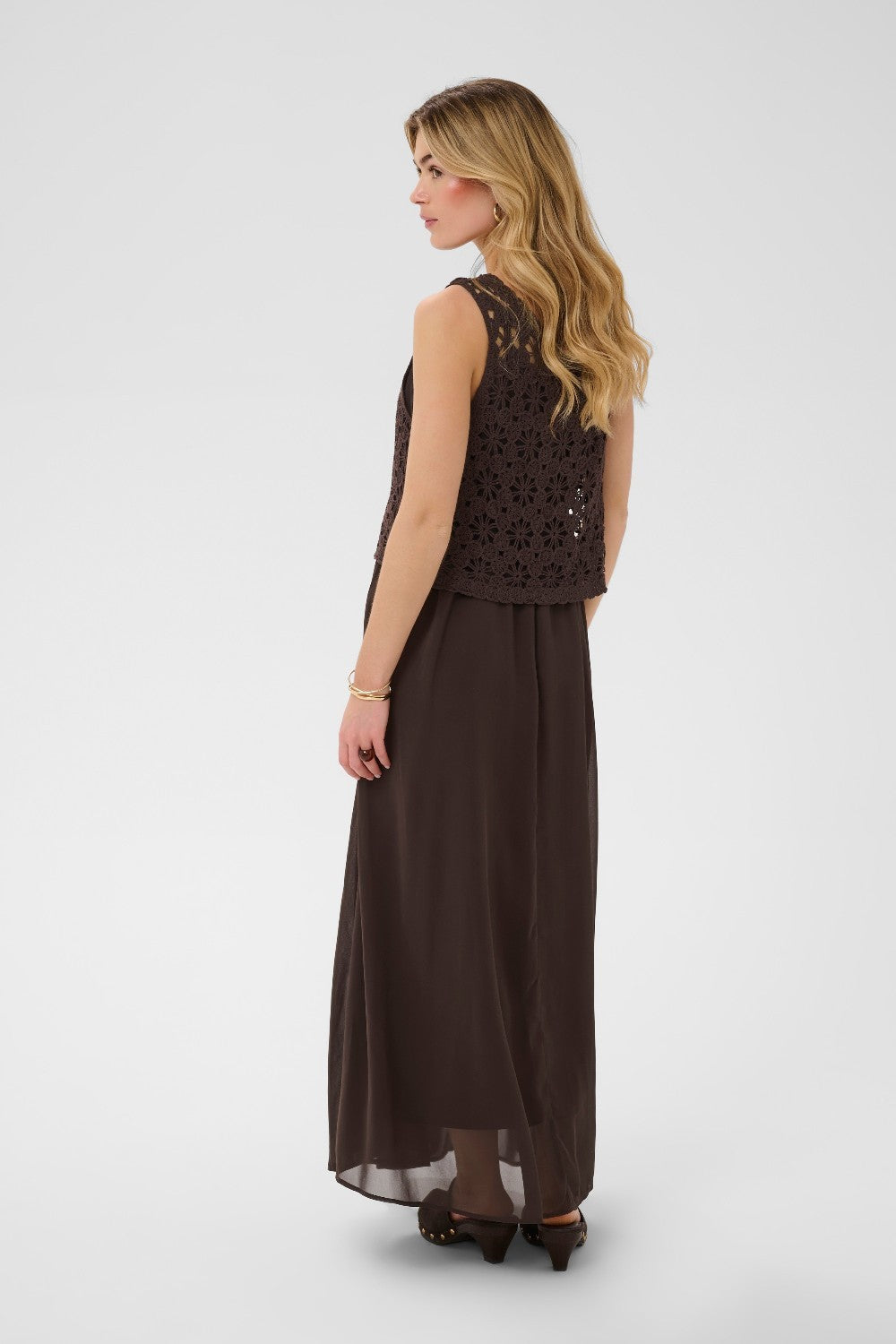 Woman wearing a brown dress with crochet detailing on a white background