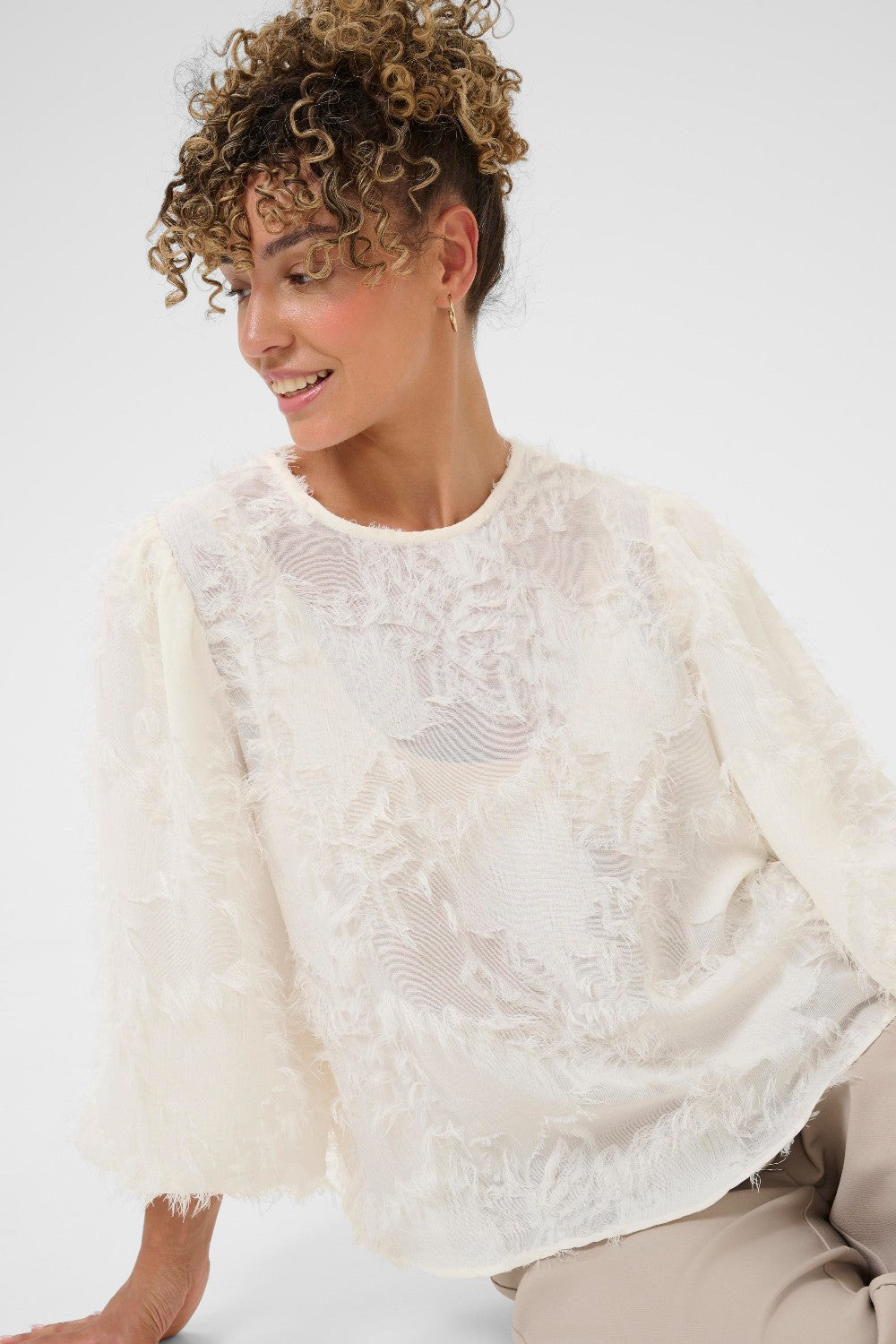 Woman wearing a white lace top against a white background