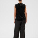 Person wearing a black sleeveless top and dark pants on a white background