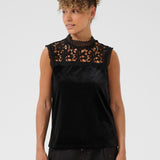 Woman wearing a black sleeveless top with lace detailing on a white background