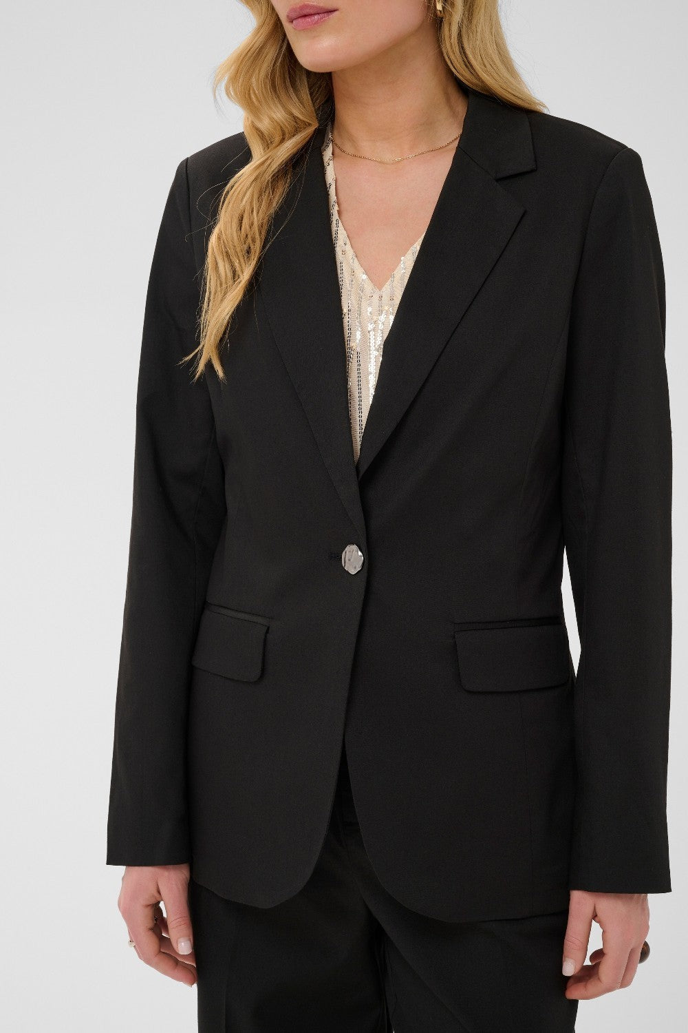Person wearing a black blazer over a patterned top on a white background