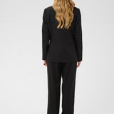 Person wearing a black suit standing against a white background
