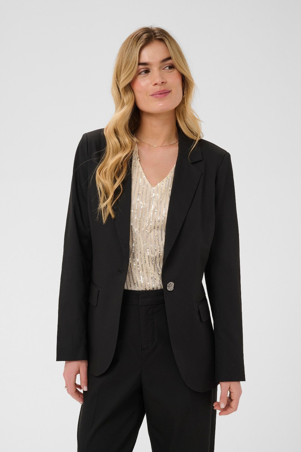 Woman wearing a black blazer over a patterned top on a white background