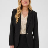 Woman wearing a black blazer over a patterned top on a white background