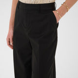 Black pants worn with a gold sequin top on a white background