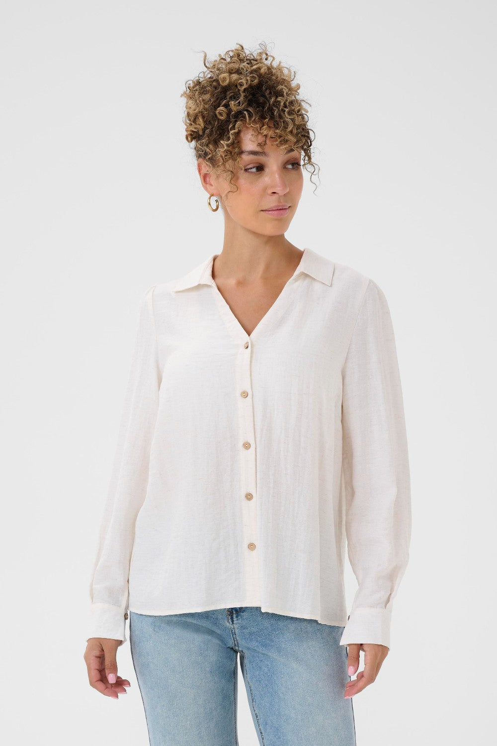 Woman wearing a white button-up shirt and light blue jeans on a white background