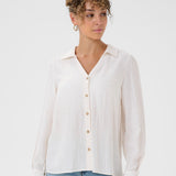 Woman wearing a white button-up shirt and light blue jeans on a white background