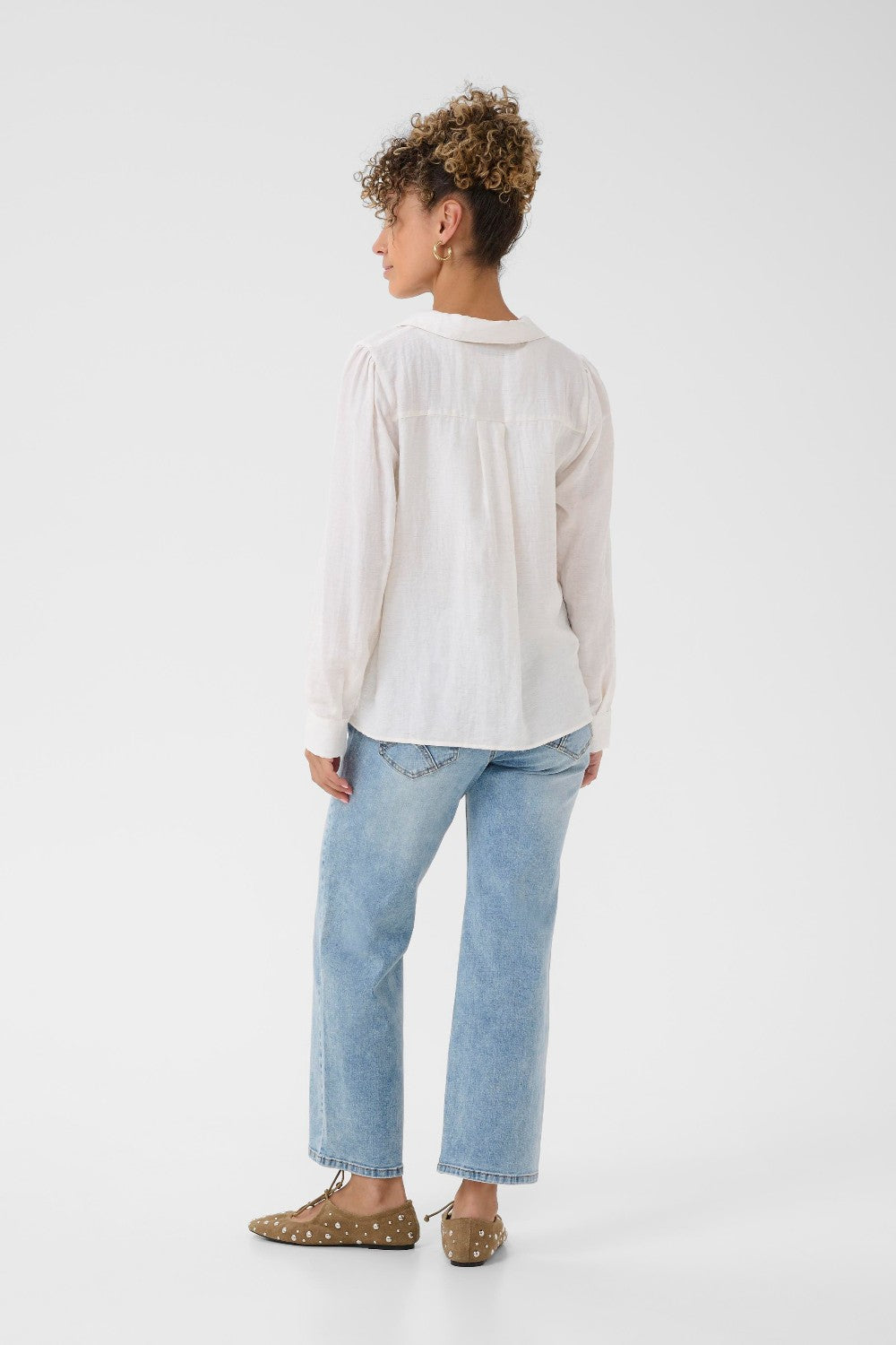 Person wearing a white shirt and light blue jeans on a white background