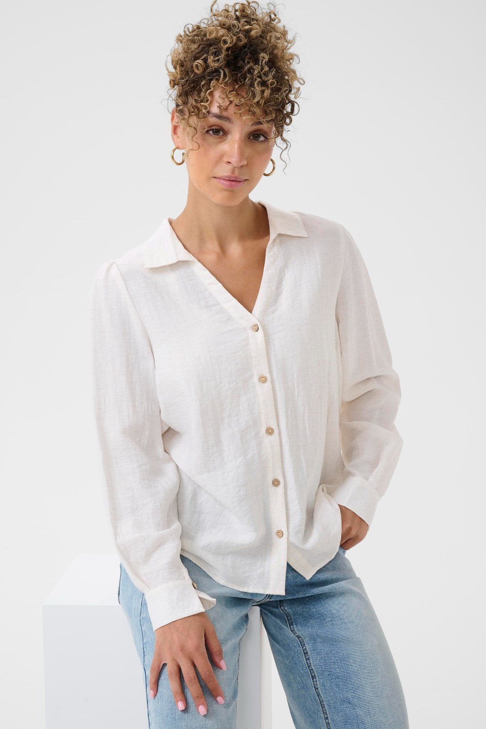 Woman wearing a white button-up shirt and blue jeans on a white background