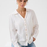 Woman wearing a white button-up shirt and blue jeans on a white background
