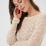 Woman wearing a beige lace top against a white background