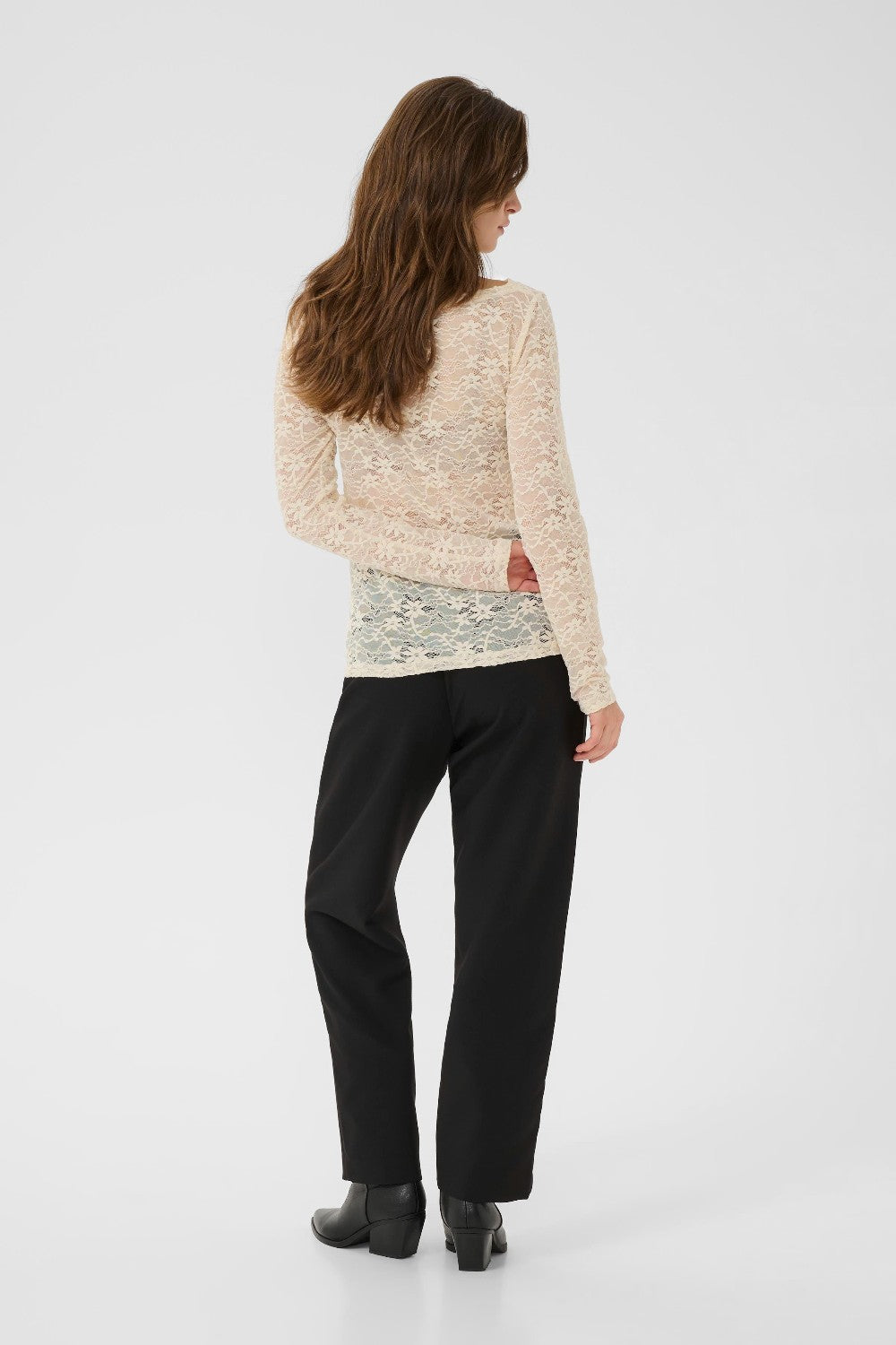 Woman wearing a beige sweater and black pants on a white background