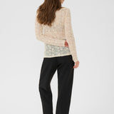 Woman wearing a beige sweater and black pants on a white background