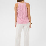 Woman wearing a pink sleeveless top and white pants on a white background