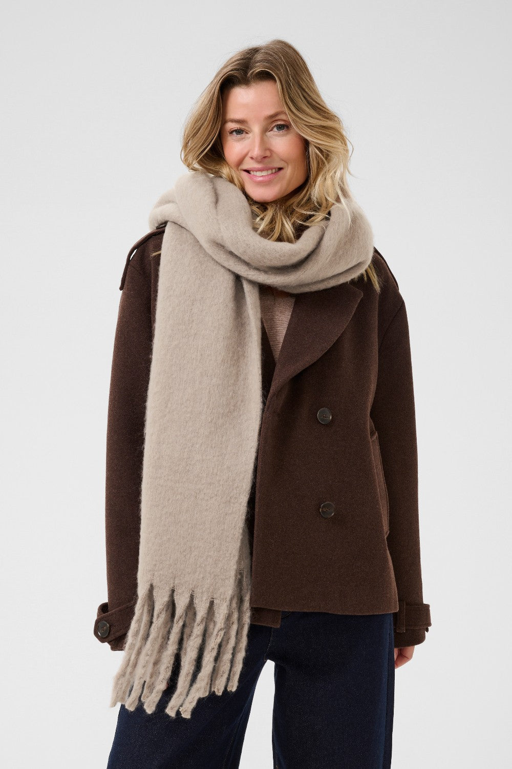 Woman wearing a brown coat and beige scarf on a white background