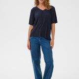 Woman wearing a navy blue top and blue jeans on a white background