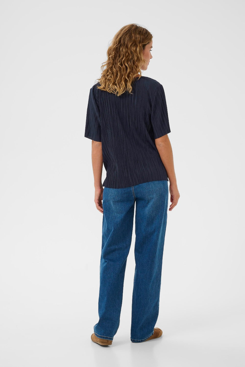 Woman wearing a dark blue top and blue jeans on a white background