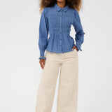 Woman wearing a blue shirt and beige pants on a white background