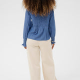 Person wearing a blue blouse and beige pants on a white background
