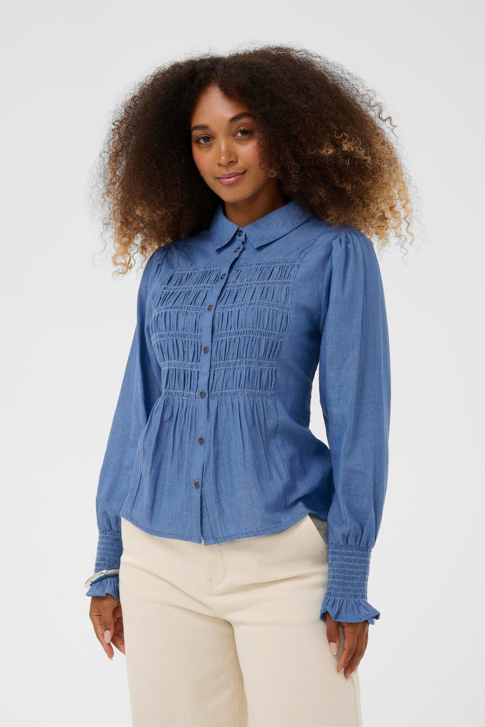 Woman wearing a blue blouse with smocked details on a white background