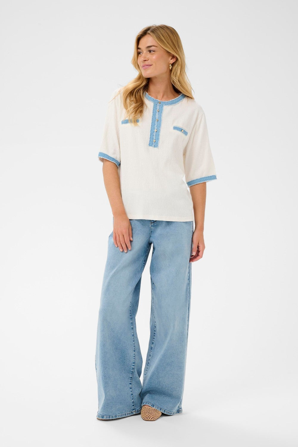 Woman wearing a white blouse with blue accents and light blue jeans on a white background