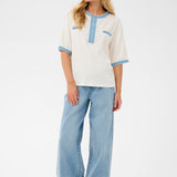 Woman wearing a white blouse with blue accents and light blue jeans on a white background