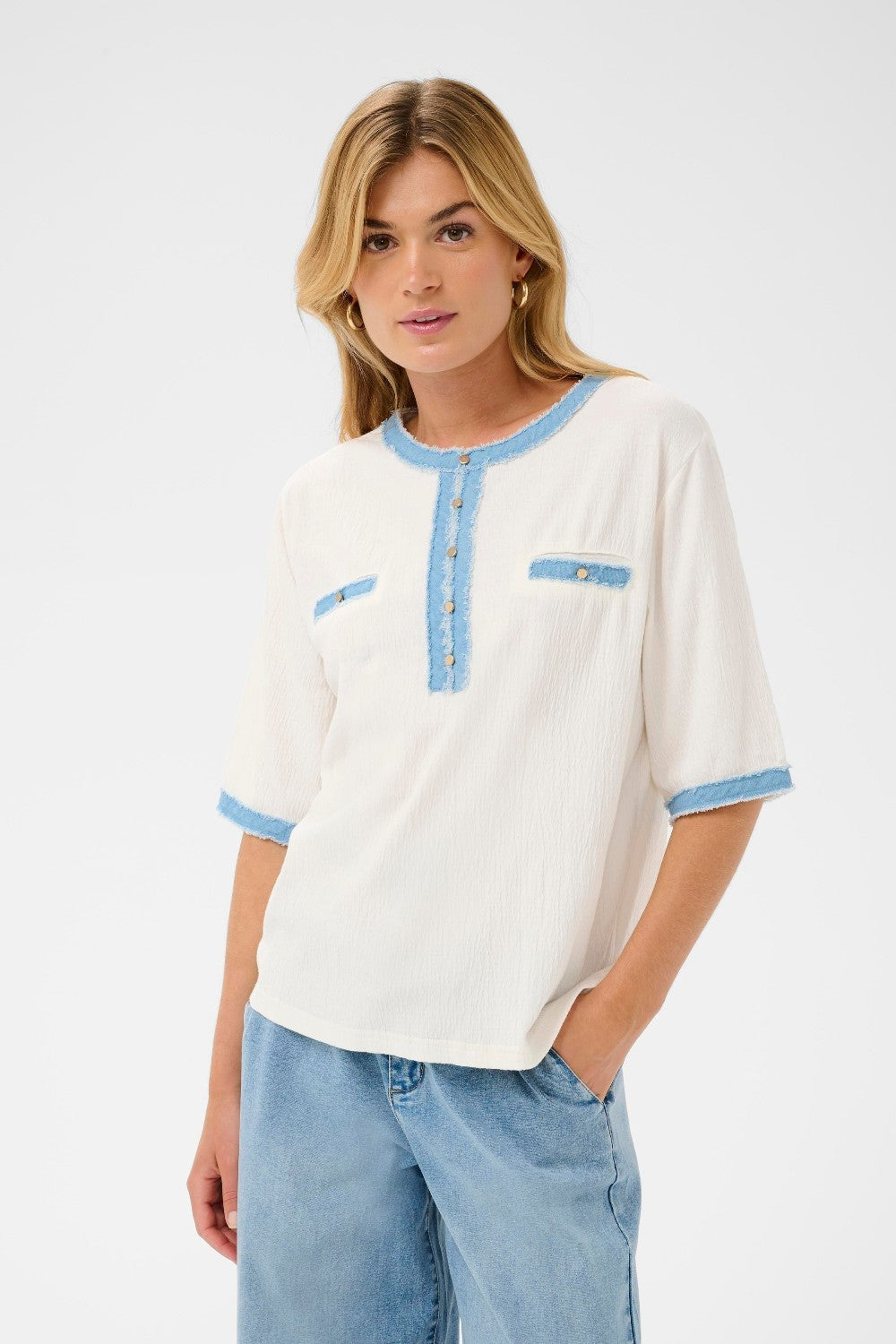 Woman wearing a white blouse with blue accents and light blue jeans on a white background