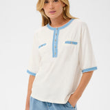 Woman wearing a white blouse with blue accents and light blue jeans on a white background