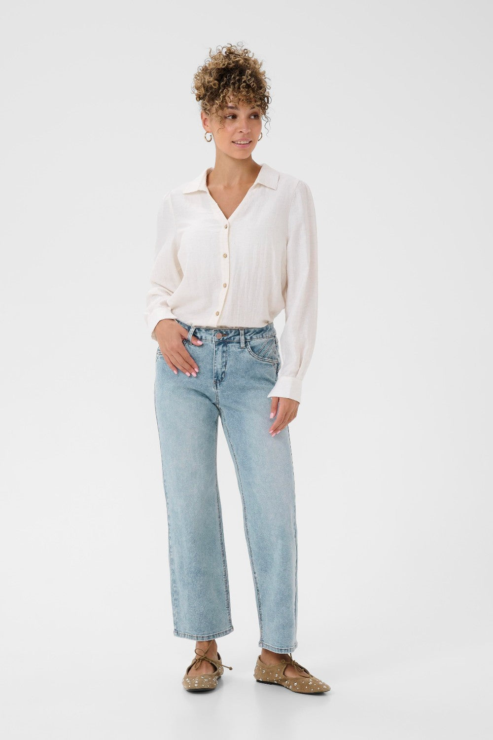 Woman wearing a white shirt and light blue jeans on a white background