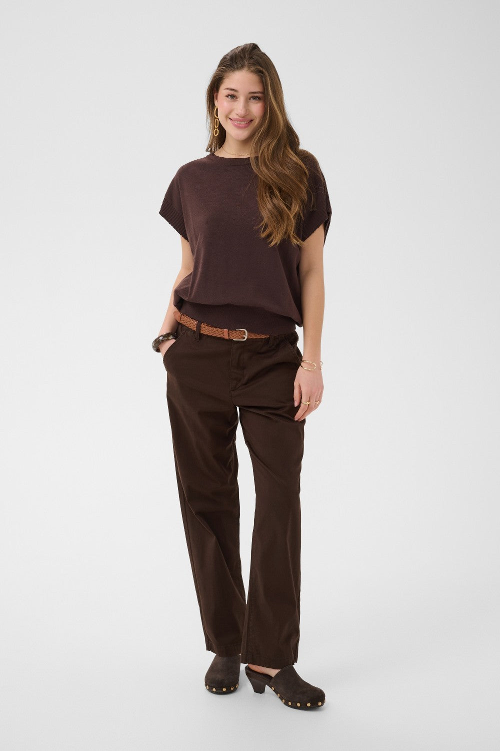 Woman wearing a brown outfit with a belt on a white background