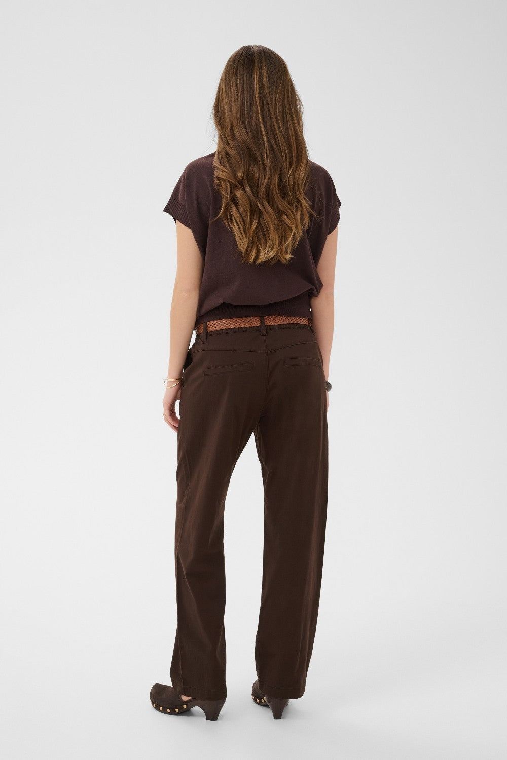 Person wearing a brown outfit with a belt on a white background