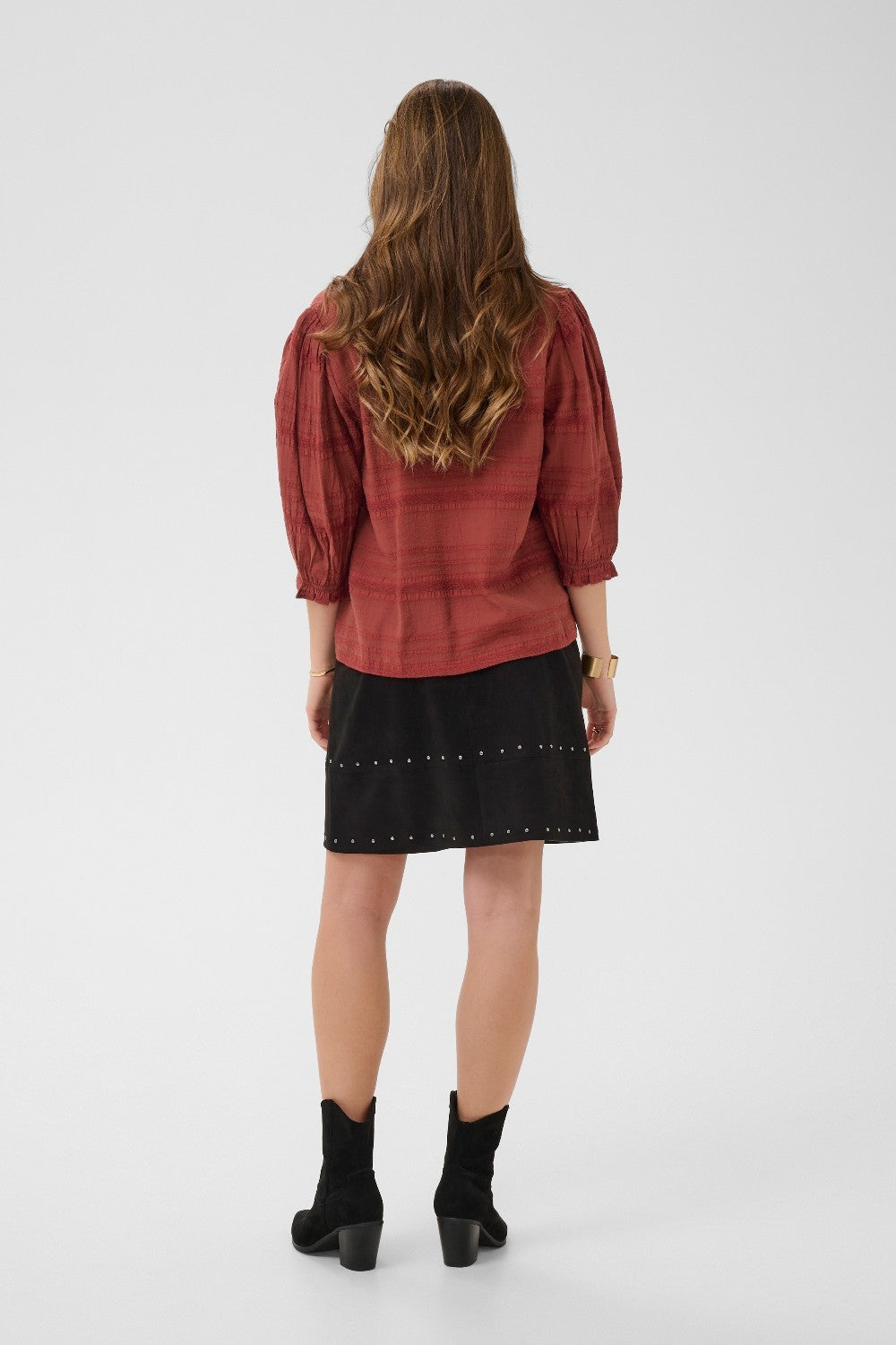 Person wearing a red shirt and black skirt on a white background