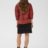 Person wearing a red shirt and black skirt on a white background
