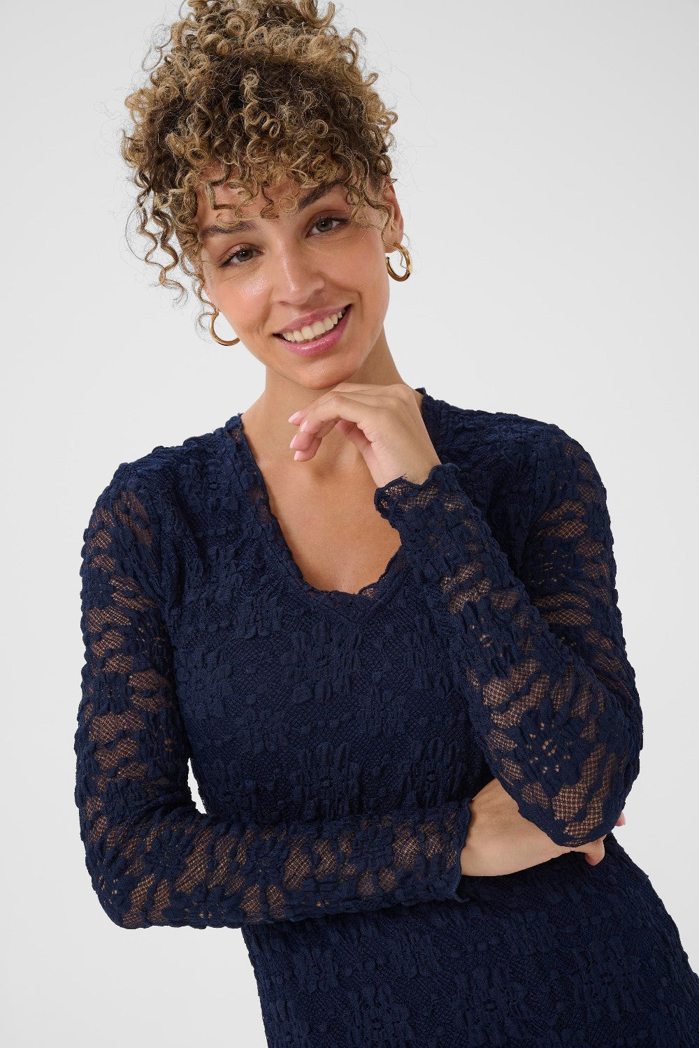 Woman wearing a navy blue dress with sheer sleeves against a white background