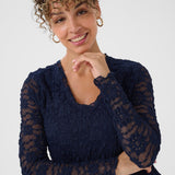 Woman wearing a navy blue dress with sheer sleeves against a white background