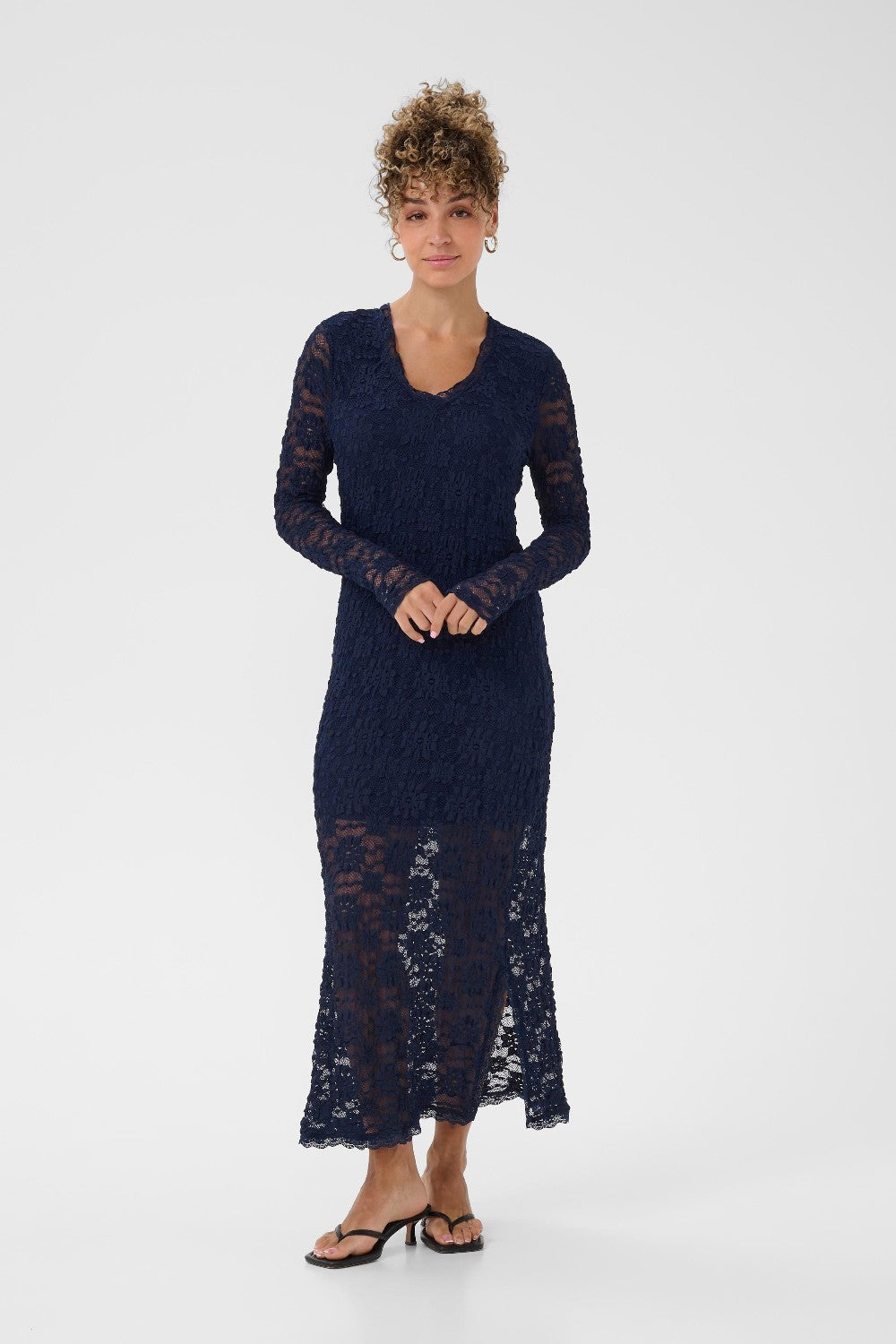 Woman wearing a navy blue lace dress on a white background