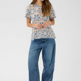 Woman wearing a patterned top and blue jeans on a white background