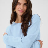 Woman wearing a light blue sweater against a white background