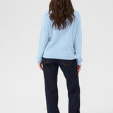 Person wearing a light blue sweater and dark pants on a white background