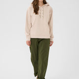 Woman wearing a beige hoodie and green pants on a white background