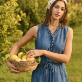 Woman in a denim outfit holding a basket of lemons in an orchard