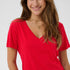 Woman wearing a red V-neck t-shirt against a plain background