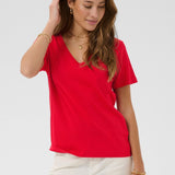 Woman wearing a red top and white pants on a plain background