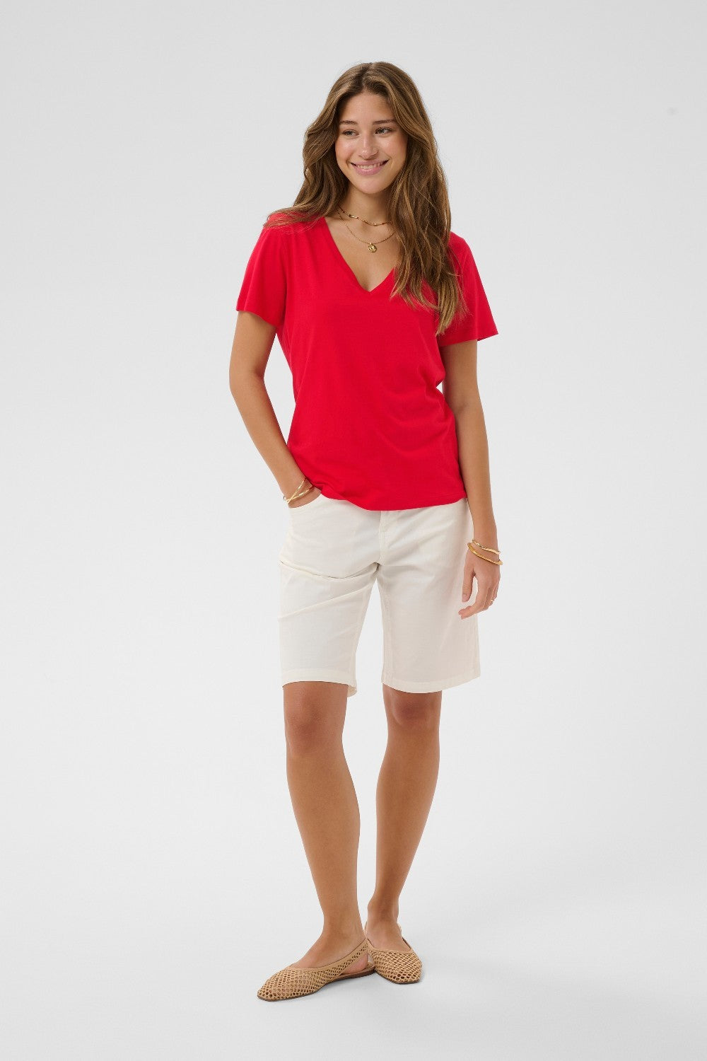 Woman wearing a red shirt and white shorts on a white background