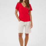 Woman wearing a red shirt and white shorts on a white background