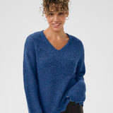Woman wearing a blue sweater against a plain background
