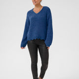 Woman wearing a blue sweater and black pants on a white background