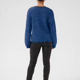Person wearing a blue sweater and black pants on a white background